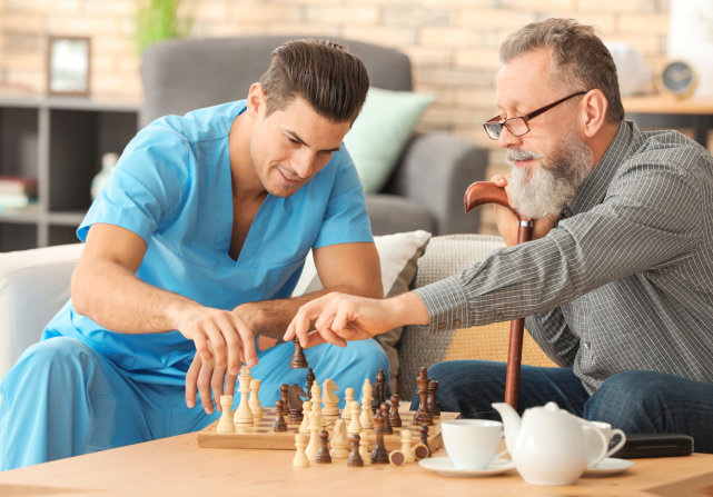 senior playing chess with a nurse